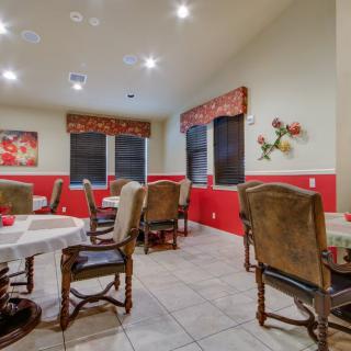 A cozy dining room with multiple tables and chairs, adorned with decorative paintings and soft lighting.