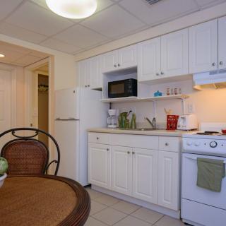 A small kitchen with white cabinets, a microwave, and a dining area.