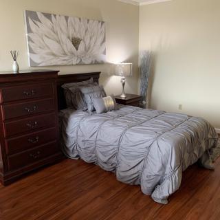 A cozy bedroom with a neatly made bed, a wooden dresser, and elegant decor.