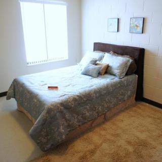 A neatly arranged bedroom with a bed, pillows, and soft lighting.