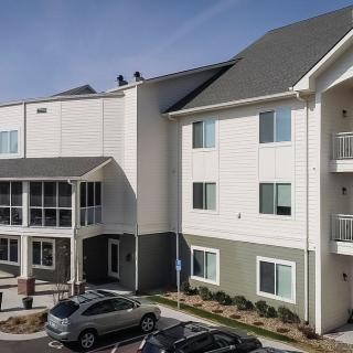 A view of a modern apartment building with a parking lot and cars in front.