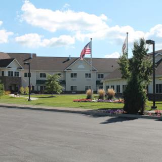 A hotel building with flags in front, surrounded by landscaped grounds under a clear blue sky.