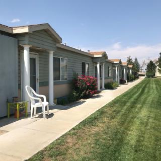 A row of apartments with a well-maintained lawn and outdoor seating.