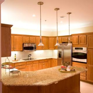 A modern kitchen featuring wooden cabinets, an island countertop with granite, and stylish pendant lighting.