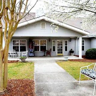 A cozy residential house with a front yard and pathway, surrounded by trees.