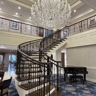 A luxurious interior featuring a grand staircase, elegant chandelier, and a grand piano.
