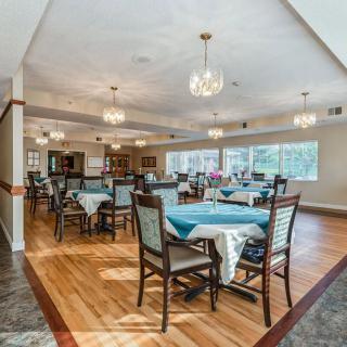 A spacious dining room with elegantly set tables and chandeliers.