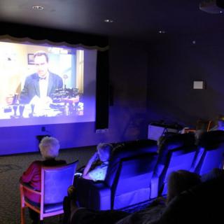 A group of people watching a movie in a cozy home theater setting.