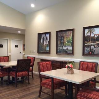 A cozy dining area with tables and chairs, adorned with wall paintings and ambient lighting.