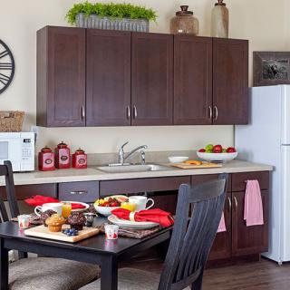 A cozy kitchen with a dining table set for breakfast, featuring dark wooden cabinets and modern appliances.