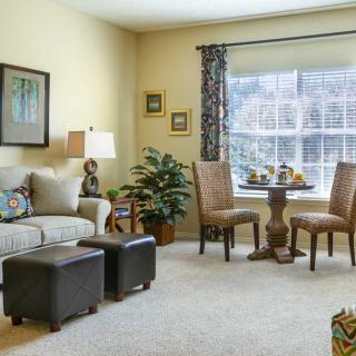 A cozy living room with a sofa, table and chairs, large window, and tasteful decorations.