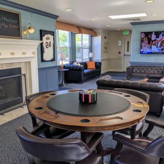 A cozy game room featuring a poker table, fireplace, and comfortable couches with a television mounted on the wall.