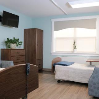 A well-lit and organized hospital patient room equipped with essential furniture.