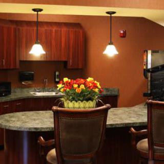 A cozy kitchen with pendant lighting, a granite countertop, and vibrant flowers as a centerpiece.