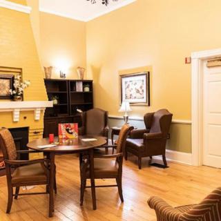 A cozy living room with comfortable chairs, a wooden table, and a warm fireplace.