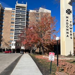 View of a residential tower with autumn trees and clear blue sky.