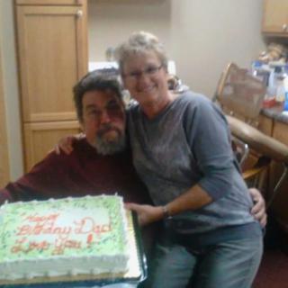 A couple celebrating with a cake in the kitchen.