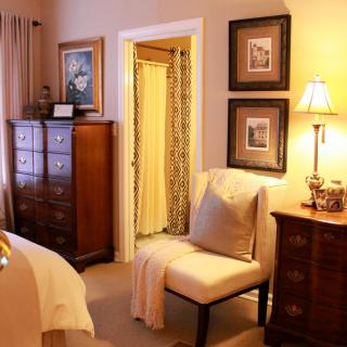 A cozy bedroom with elegant furniture, warm lighting, and tasteful wall art.