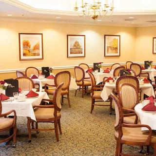 An elegant dining room with neatly arranged tables and chairs, adorned with artwork on the walls.