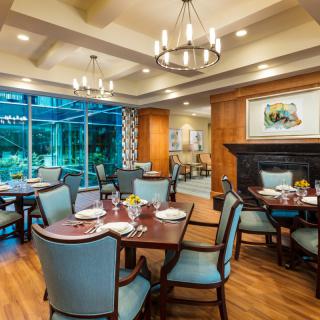 An elegant dining area with stylish furniture, chandeliers, and large windows overlooking a garden.