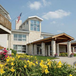 A two-story building with a flag, surrounded by landscaped flowers and a bright blue sky.