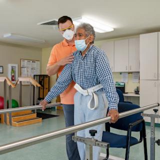 A healthcare professional assists an elderly patient during physical therapy, focusing on rehabilitation in a supportive environment.