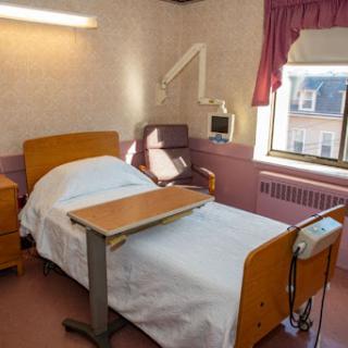 A well-lit hospital patient room featuring a bed, bedside table, and window.