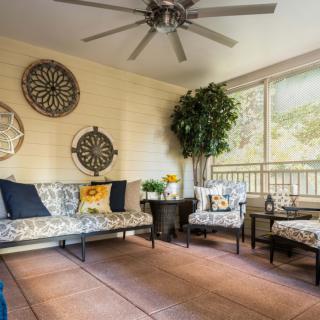 A cozy sunroom featuring stylish furniture, wall art, and large windows with natural lighting.