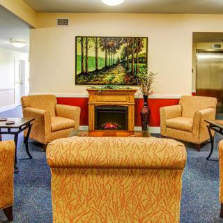 A cozy living room with comfortable seating and a fireplace, adorned with artwork on the wall.