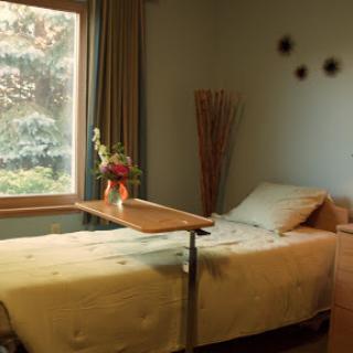 A serene and inviting bedroom with natural light streaming in through the window, featuring a neatly made bed and a decorative flower arrangement.