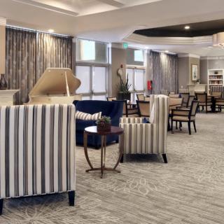 A spacious and elegantly decorated lobby with striped chairs, tables, and a piano.