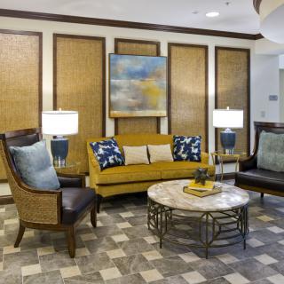 A stylishly furnished living room with a modern sofa, chairs, coffee table, and decorative lamps.