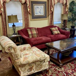 A cozy living room setup featuring a red sofa, floral armchair, and a wooden coffee table.