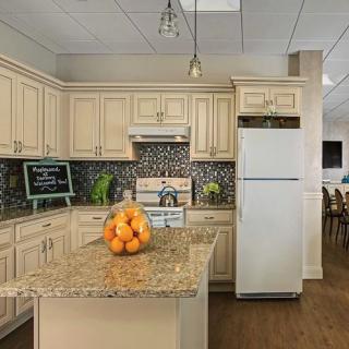 A modern kitchen with cream cabinets, a granite island countertop, and stainless steel appliances.