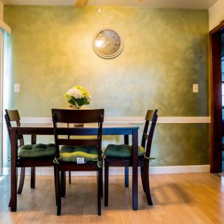 A cozy dining room with a green accent wall and a simple, elegant table setting.