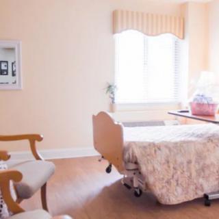 A clean and well-lit hospital room with a bed and chairs.