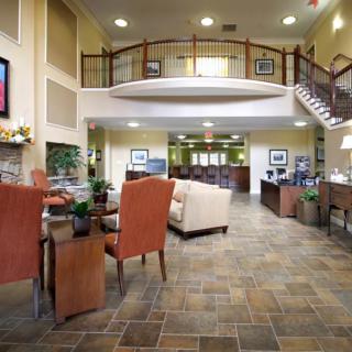 A spacious lobby interior featuring comfortable seating, a reception area, and an elegant staircase.