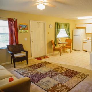 A cozy living room featuring a comfortable seating area, patterned carpet, and a dining table near the kitchen.