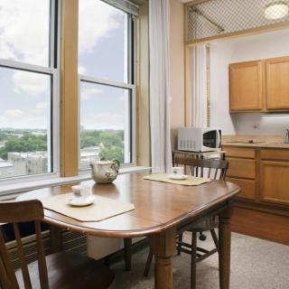 A modern kitchen and dining area with a wooden table, chairs, and large windows offering a scenic view.