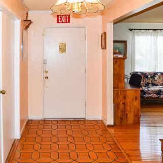 A hallway leading to a front door, featuring wooden flooring and a ceiling light.