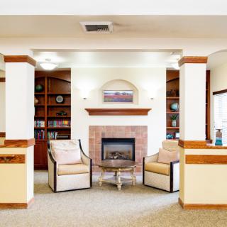 A cozy living room with armchairs and a fireplace, surrounded by bookshelves.