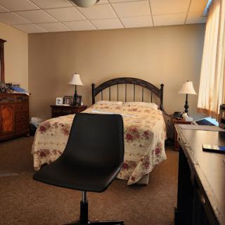 A cozy bedroom featuring a bed, nightstands with lamps, a chair, and a desk.