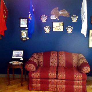 A room with a decorative couch and various military-themed items and flags on display.