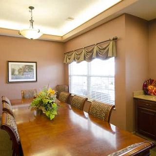 A well-lit dining room featuring a long wooden table and chairs, adorned with floral centerpiece and artwork on the wall.