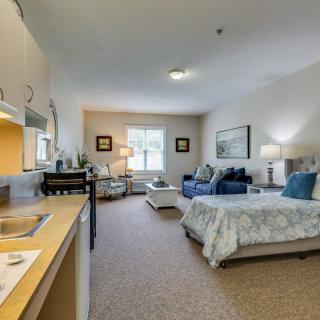 A cozy and well-furnished bedroom with a sitting area and kitchenette.