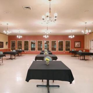 An empty banquet hall with neatly arranged tables and elegant chandeliers.