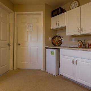 A small kitchen area with white cabinets and a mini fridge.