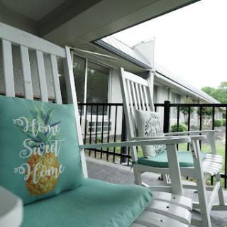 A cozy outdoor space featuring white rocking chairs with soft cushions, perfect for relaxation.