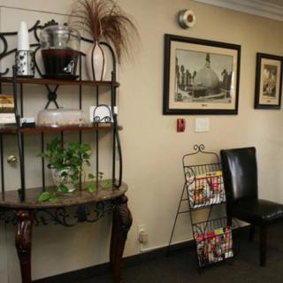 A waiting room featuring a decorative shelf, a black chair, and a magazine rack.