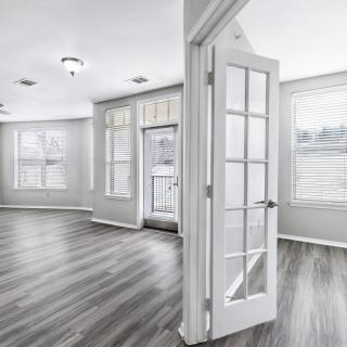A bright living space with hardwood floors, large windows, and French doors.